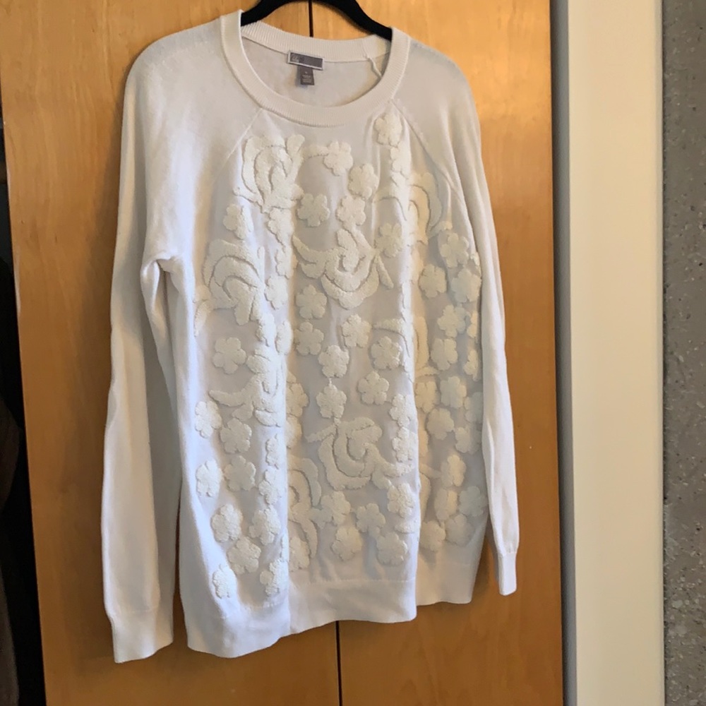 Cream sweater with embroidered detail.